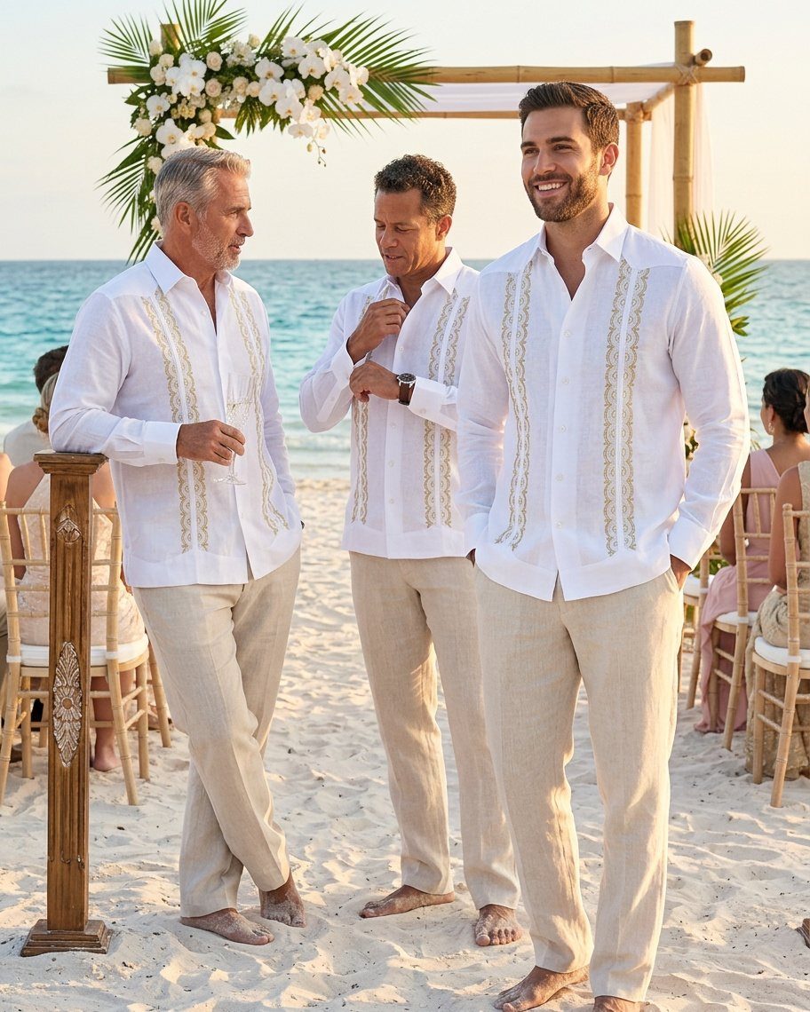 Three men in white embroidered shirts and beige linen pants on a beach.