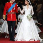 Kate Middleton in her lace Alexander McQueen wedding gown standing with Prince William.