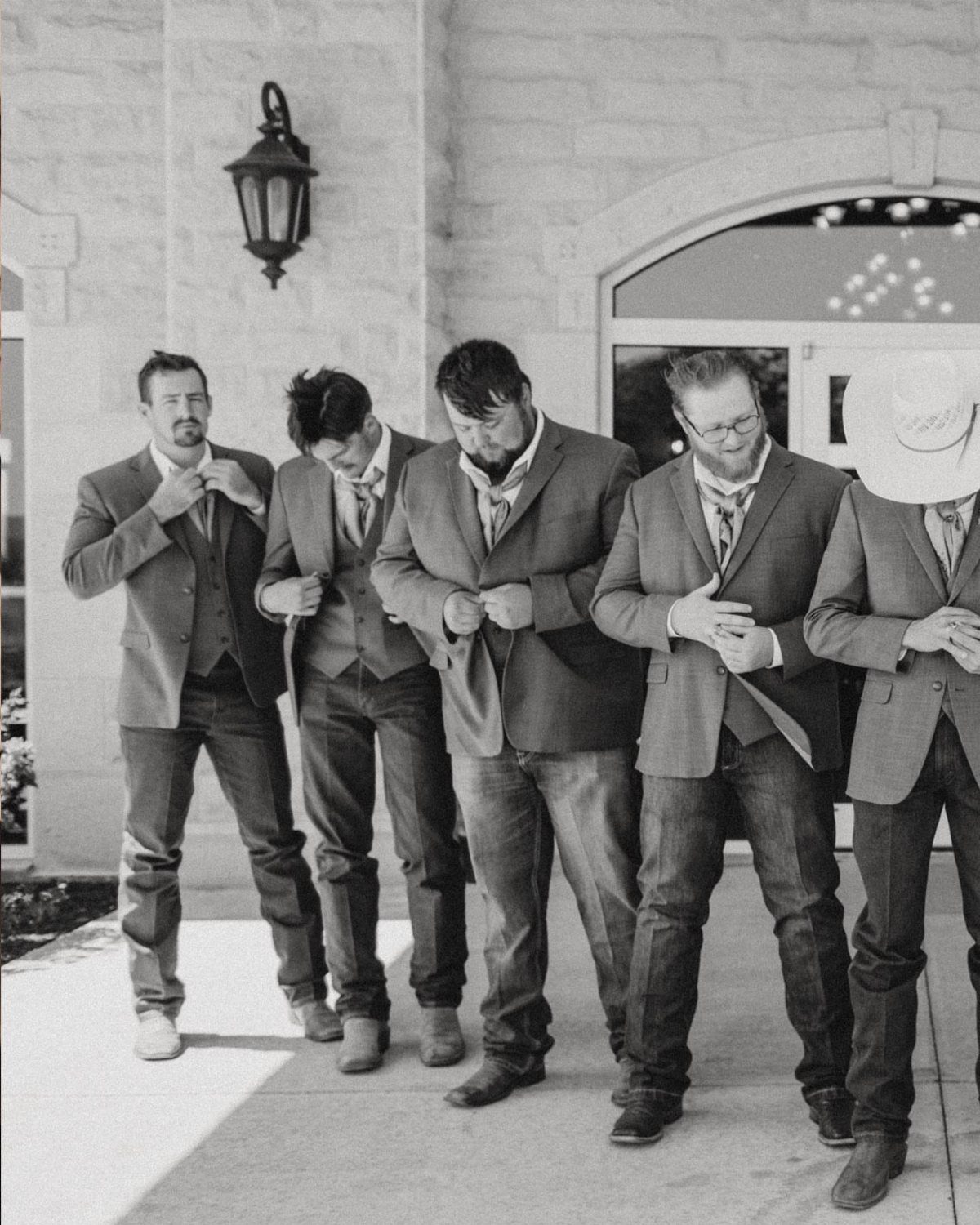 Five men wearing suit jackets and jeans, one with a cowboy hat, outdoors.