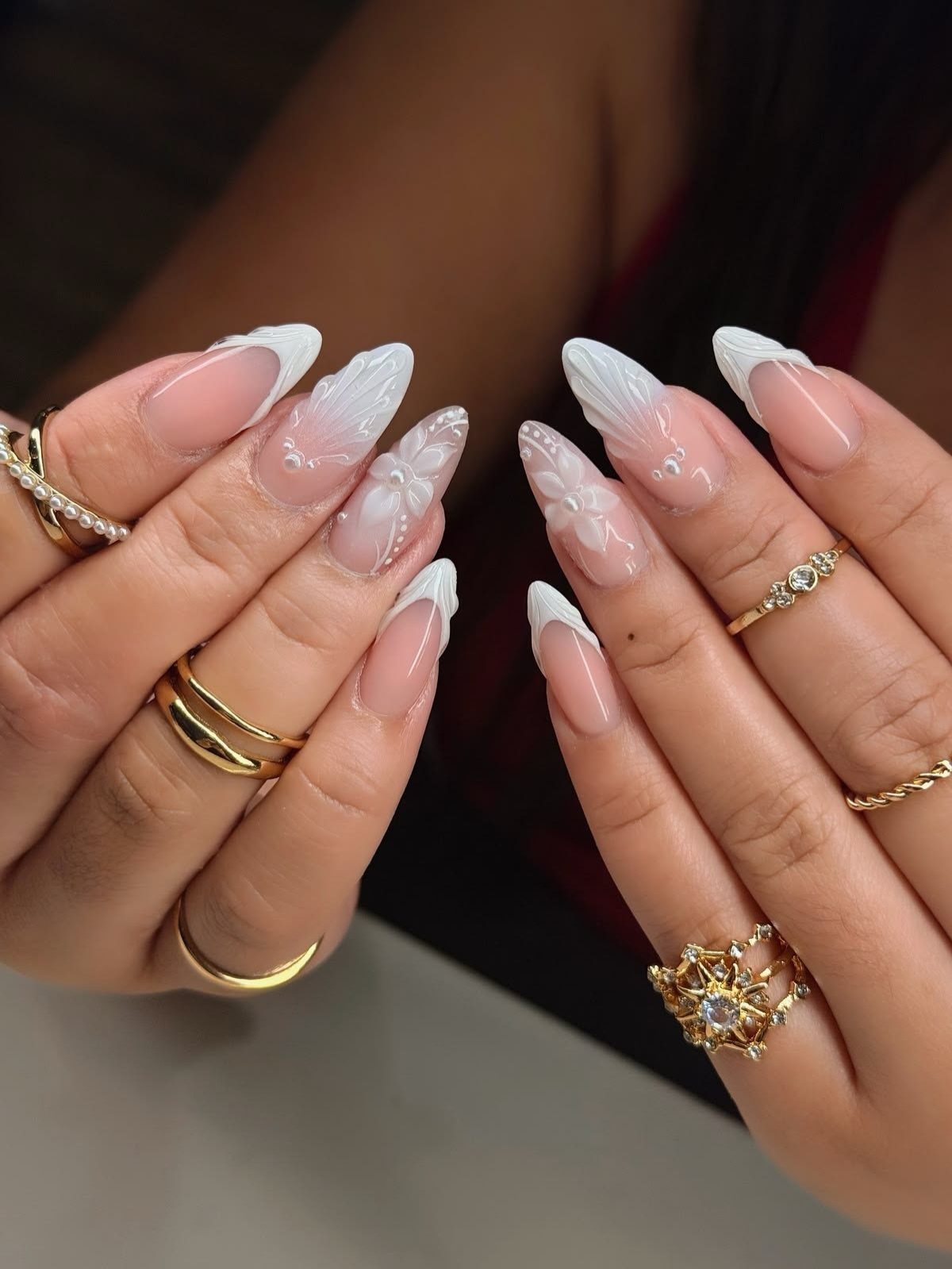 Manicured hands with white floral wedding nail art and gold rings