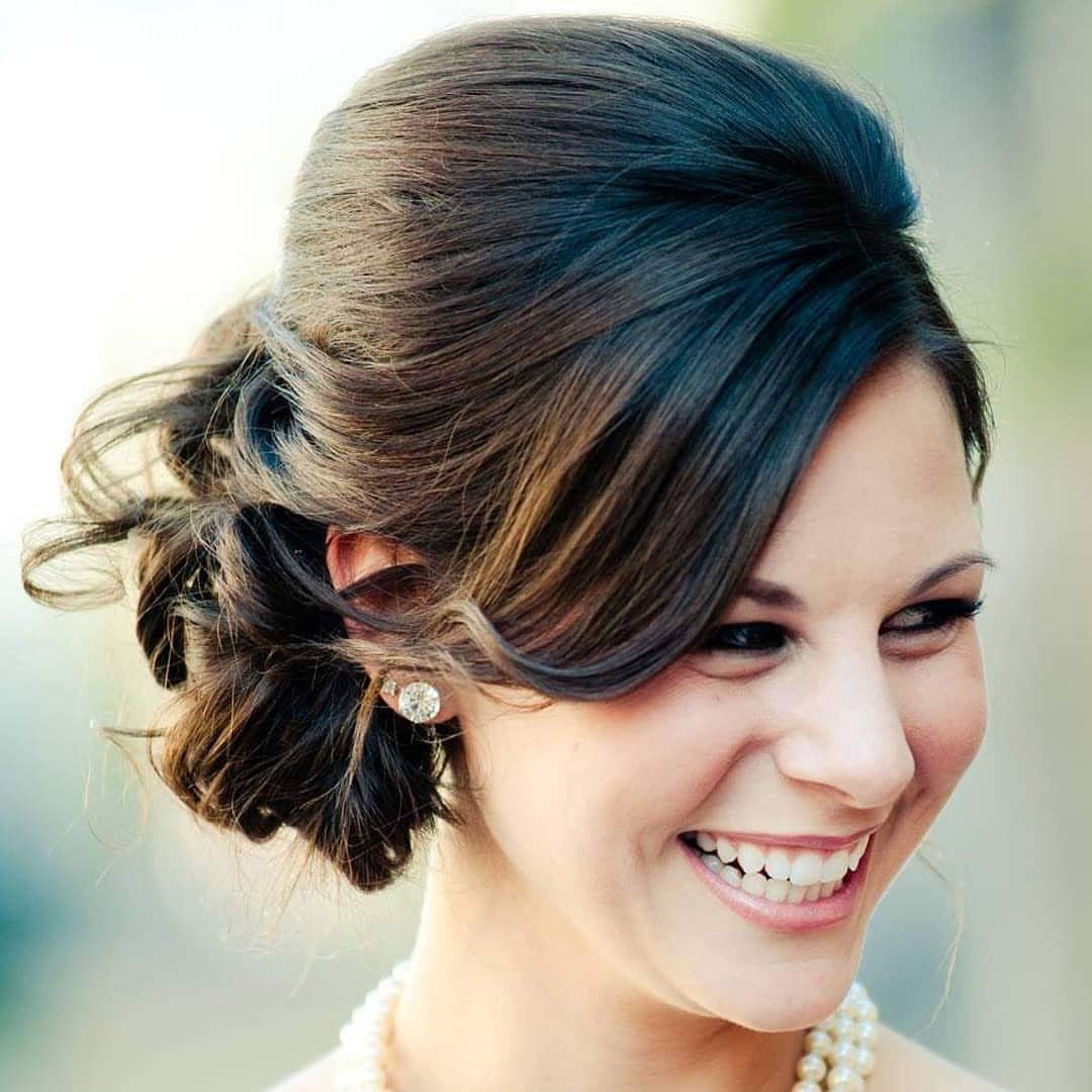 Woman with a bridal low bun updo, pearl necklace, and natural wedding makeup.