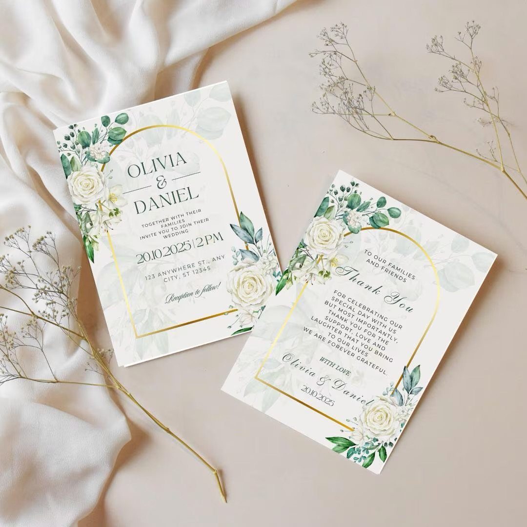 Wedding invitation cards with gold borders and white floral designs on a beige background.