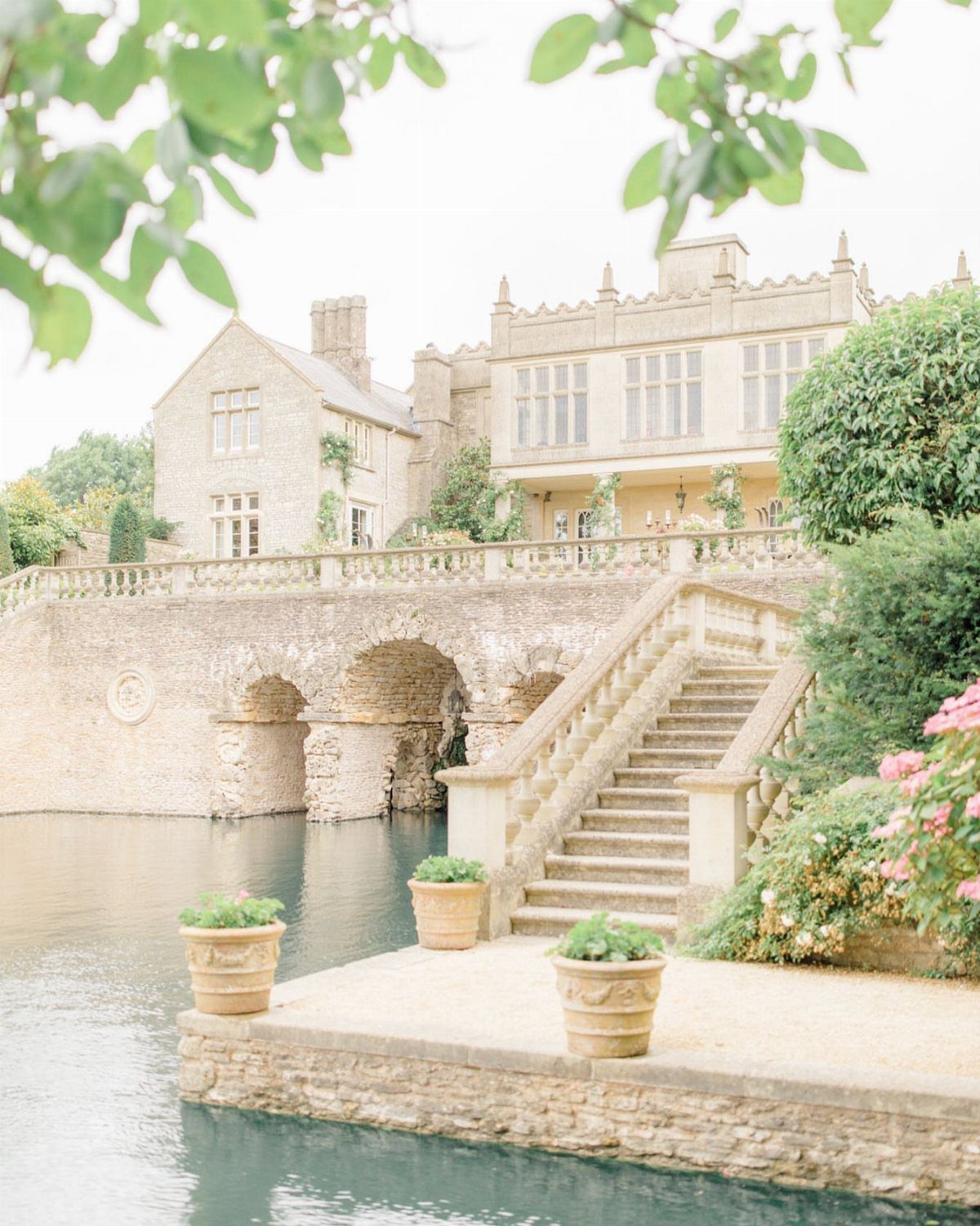 Stone manor house with arched bridge and stairs by a calm river