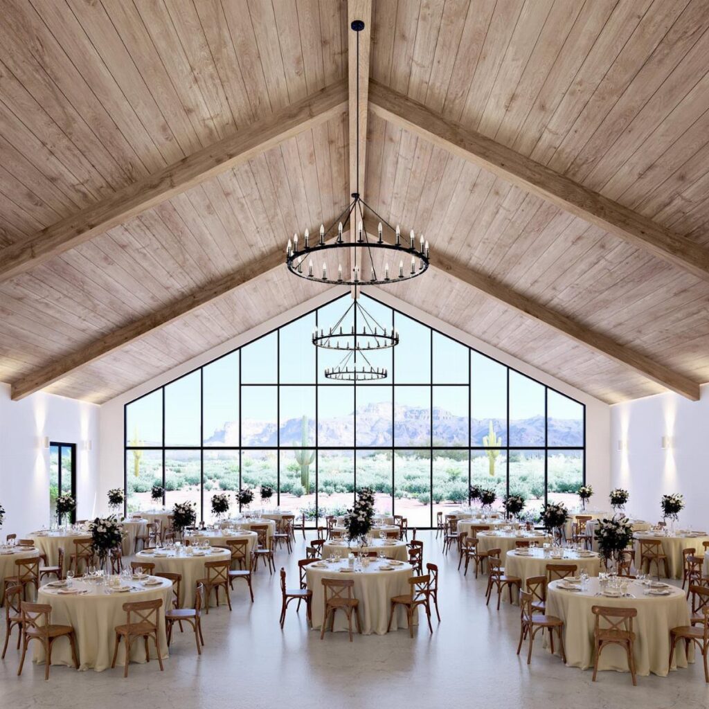 Wedding reception hall with wooden ceilings and desert views through large glass windows.
